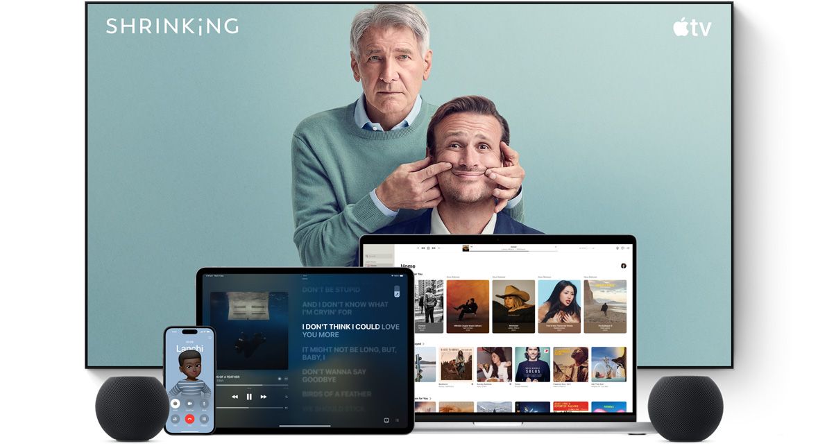 Large flat screen television showing two male characters from the Apple TV series shrinking. A MacBook Pro, an iPad, an iPhone and a Midnight HomePod mini are arranged in front.