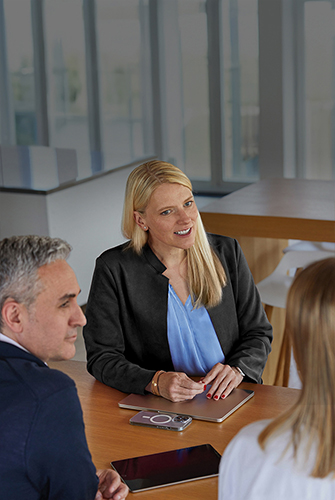 Tre persone del team Sales & Business Development di Apple che parlano tra di loro attorno a un tavolo in un’area comune.