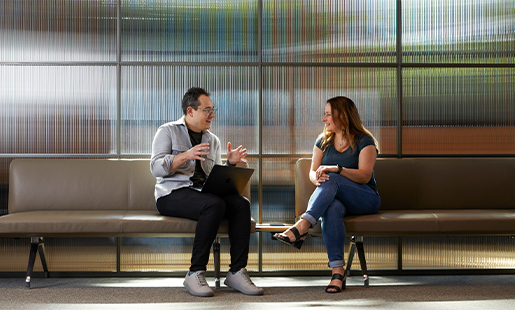Dan นั่งบนม้านั่งในสำนักงานโดยวาง MacBook ไว้บนตัก ขณะคุยกับเพื่อนร่วมงาน