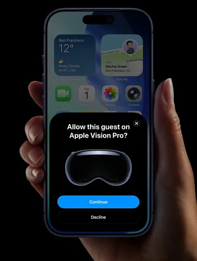 一隻手正拿著 iPhone。iPhone 螢幕上有一個視窗，當中顯示「Allow this guest on Apple Vision Pro？」訊息，底下是分別標示「Continue」和「Decline」的按鈕