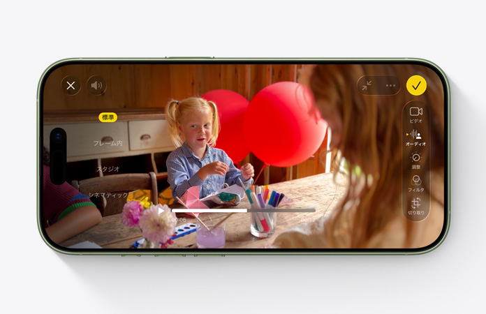 iPhone 17の前面の外観。テーブルの前に座って風船で遊ぶ子どものビデオで、オーディオミックス機能が使用されている