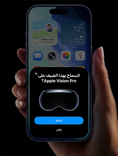 يد تحمل جهاز iPhone، شاشة iPhone تعرض نافذة عليها رسالة: 'السماح بهذا الضيف على Apple Vision Pro؟' مع زر 'متابعة' وزر 'رفض'