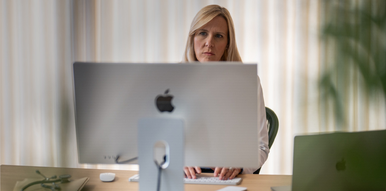 A provider looks at an iMac screen from behind her desk.