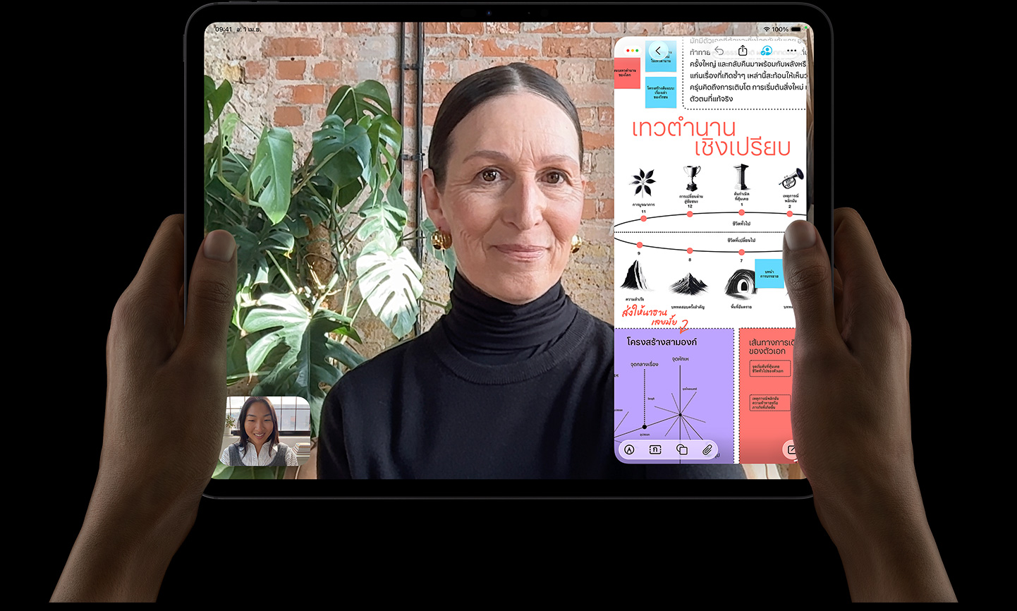 iPad Pro, front exterior, space black color, left and right hands holding in landscape orientation, rounded corners, black display bezel, display showing a FaceTime conversation being live translated, and an educational app showing a presentation of 'Comparative Mythology' with text, diagrams, and handwritten notes