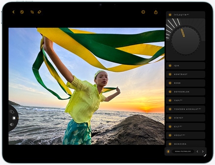 iPad Air’in önden dış görünümü, ekranda gün batımı sırasında sahilde yeşil ve sarı renkli kumaşlar tutan bir kişinin fotoğrafının düzenlendiği gösteriliyor, sağ tarafta düzenleme araçları yer alıyor