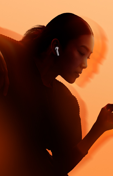 Una persona che indossa gli AirPods 5, con le braccia piegate, su uno sfondo multicolore