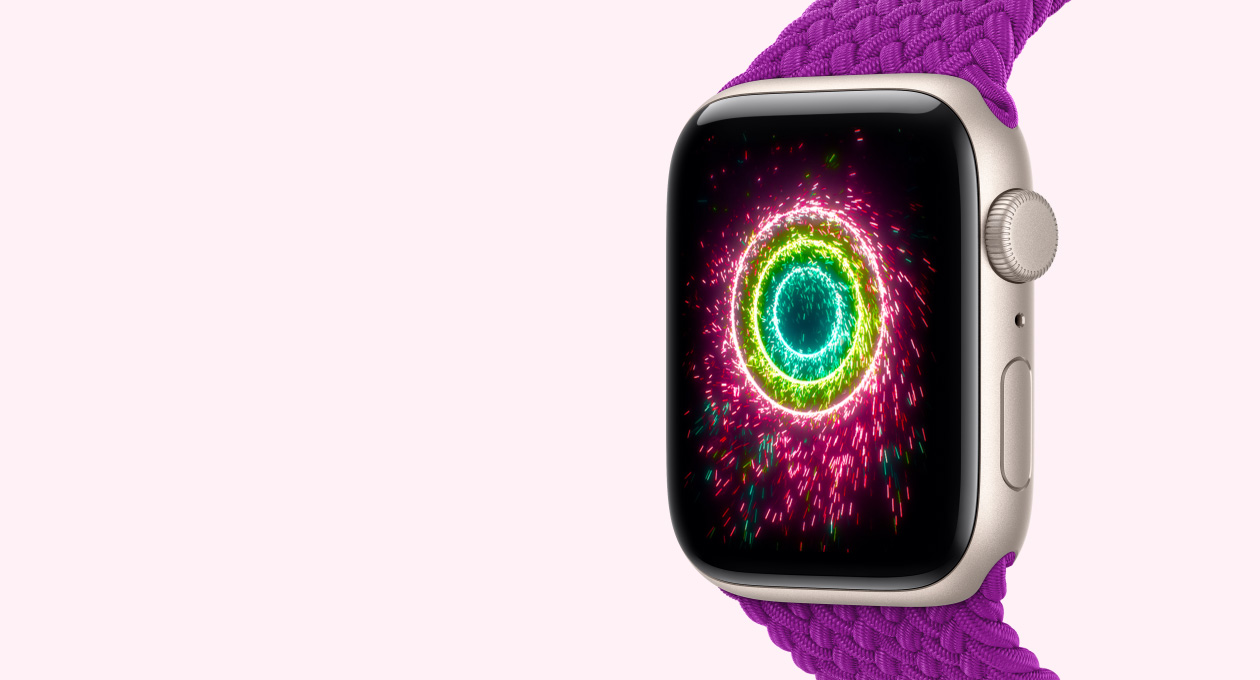 Apple Watch SE 3, starlight colour aluminum case connected to magenta colour Braided Solo Loop band, screen shows Activity rings styled as sparklers, pink, lime green, light blue concentric rings