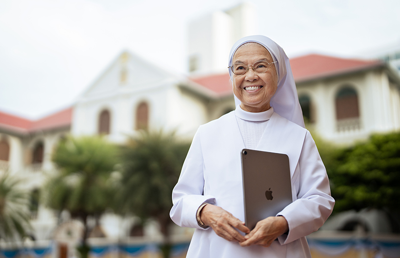 Headmistress Sister Françoise Jiranonda stands outside the school holding her iPad.