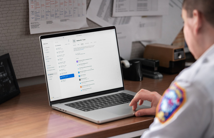 A fire department leader uses a MacBook with Apple Business Essentials open on the screen, while seated in an office