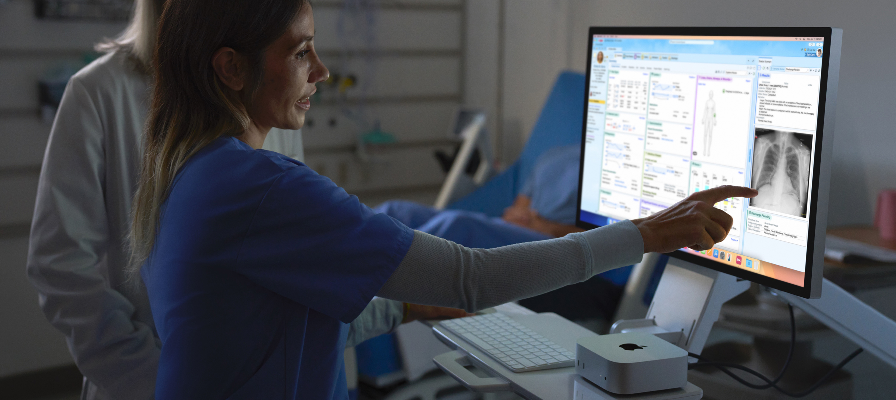 Image of nurse pointing out patient's X-ray image on iMac.