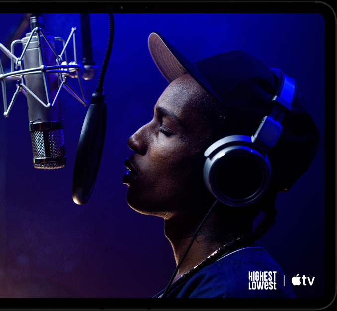 iPad Pro, landscape orientation, front exterior, space black color, rounded corners, black display bezel, display showing AppleTV+ playing a scene from  the Apple TV original film Highest 2 Lowest with ASAP Rocky as Yung Felon rapping into a microphone