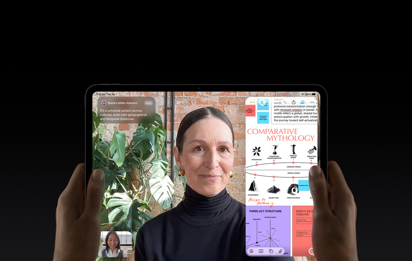 „iPad Pro“, priekinė pusė, kosminės juodos spalvos, laikomas horizontalioje padėtyje kairėje ir dešinėje rankose, užapvalinti kampai, juodas ekrano rėmelis, ekrane rodomas „FaceTime“ pokalbis, kuris yra verčiamas tiesiogiai, ir mokomoji programa, kurioje rodomas pristatymas „Lyginamoji mitologija“ su tekstu, diagramomis ir ranka rašytomis pastabomis