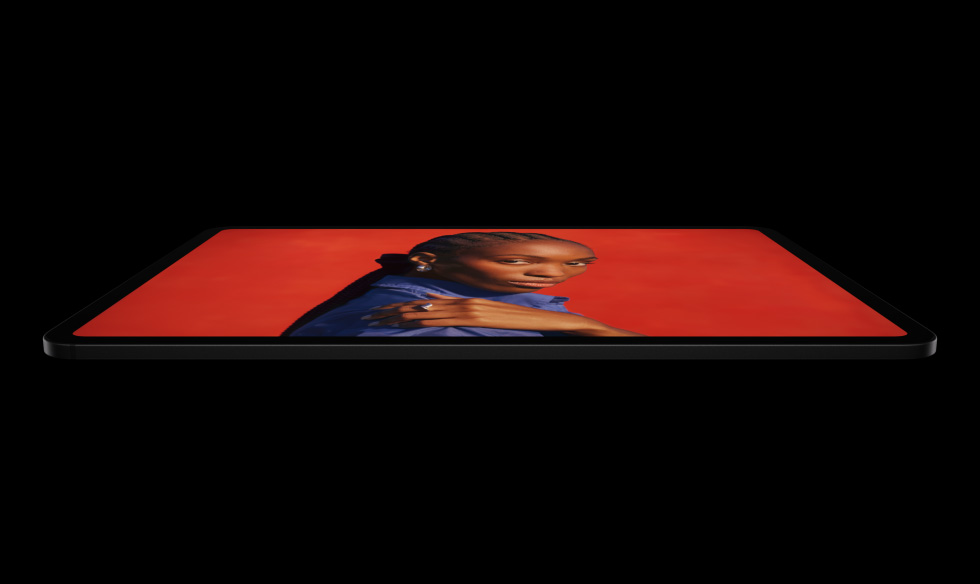 Imagem lateral do iPad Pro preto-espacial na horizontal, mostrando os cantos arredondados e a tela com borda preta, que exibe uma imagem em vermelho vibrante de uma pessoa posando com a mão no ombro e vestindo uma camisa azul