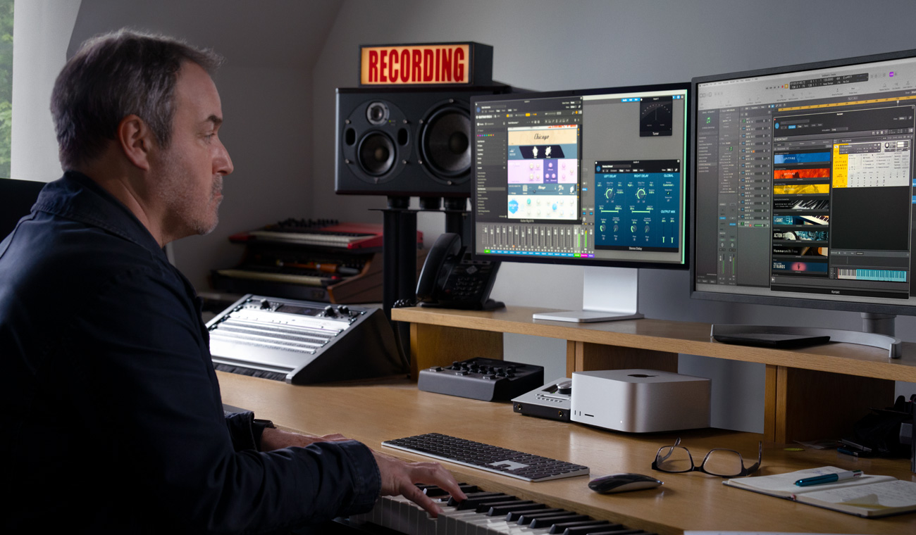 Bir müzisyen piyano kullanarak Mac Studio ve Studio Display’de ses miksleri yapıyor