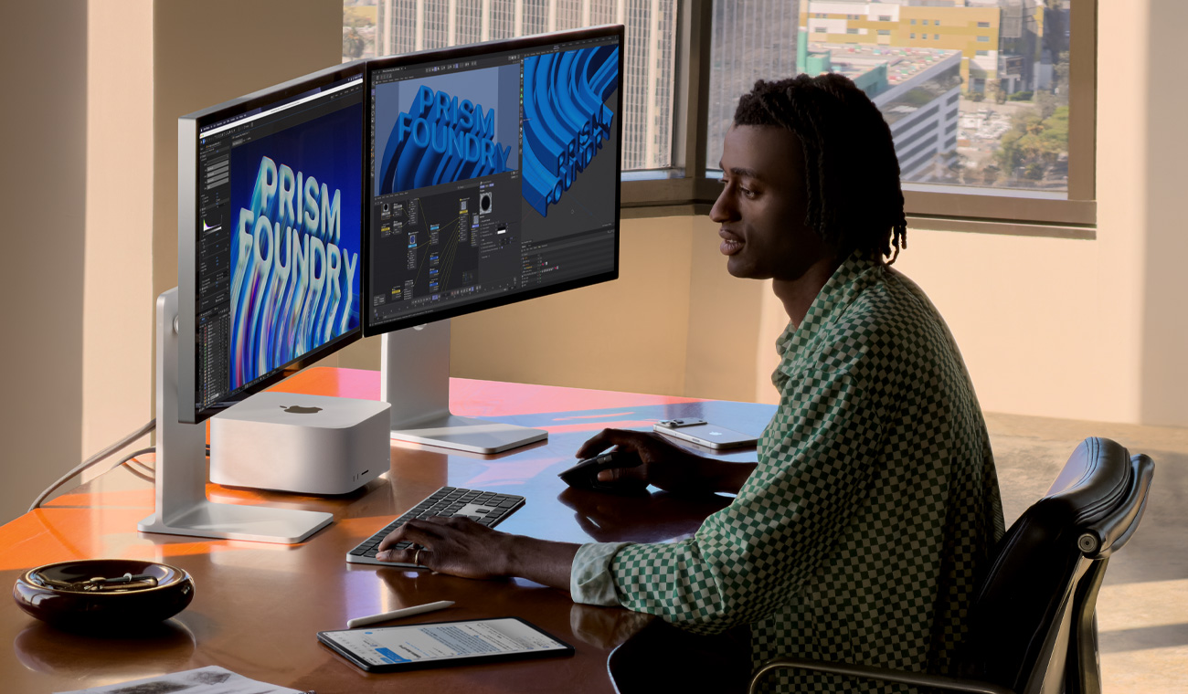 Uma profissional usando o Mac Studio com três monitores para editar arquivos.