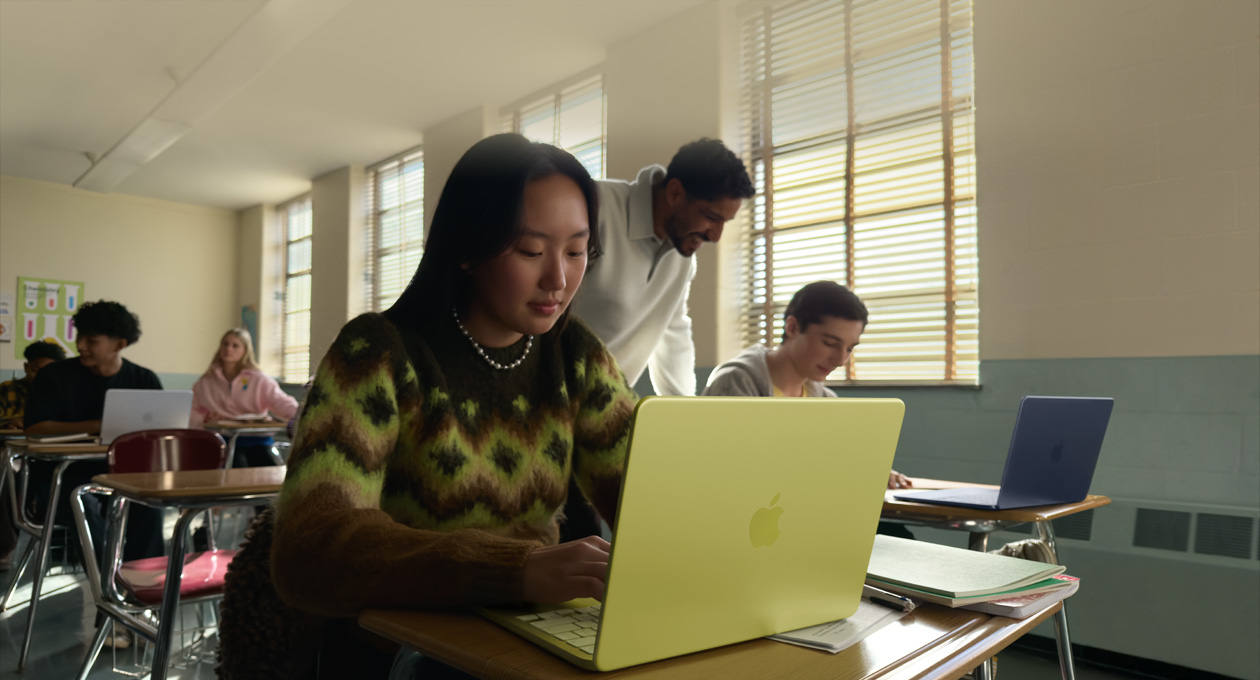 一位學生在課室中不插電使用橘黃色 MacBook Neo