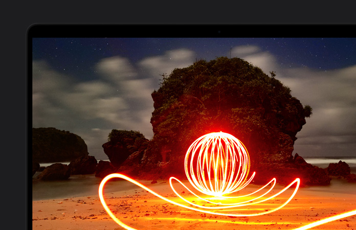 Écran de MacBook Pro affichant une installation artistique extrêmement lumineuse sur une plage, mettant en valeur le contraste de l’écran grâce à la gamme dynamique extrême