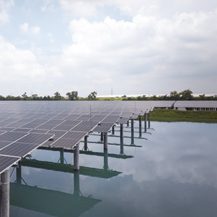 A solar panel array installed over water under a cloudy sky