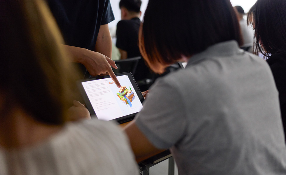 A person shares feedback on an object on a tablet screen in a classroom setting